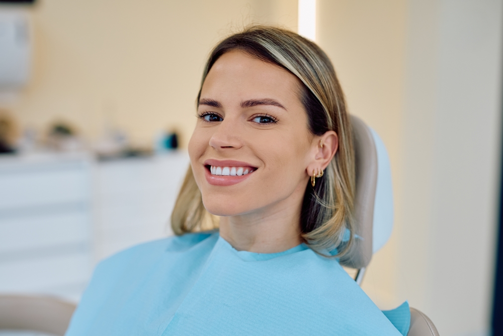 Cosmetic Dentistry in La Mesa, CA: Confident Patient Smile Smiling woman in a blue dental bib seated in a dental chair during a cosmetic dentistry visit in La Mesa, CA