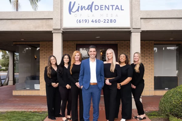 Dr. Maysam and the Kind Dental of La Mesa team smiling on the brick walkway outside their dental office in La Mesa, CA