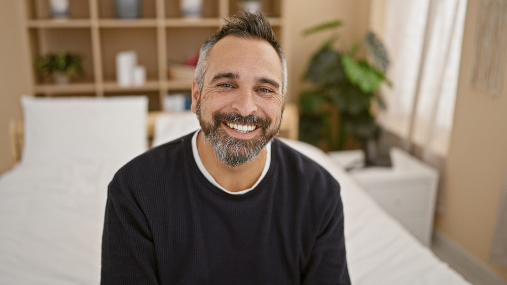 Smiling man with a gray beard in a black sweater at home, reflecting the confidence of professional whitening in La Mesa, CA